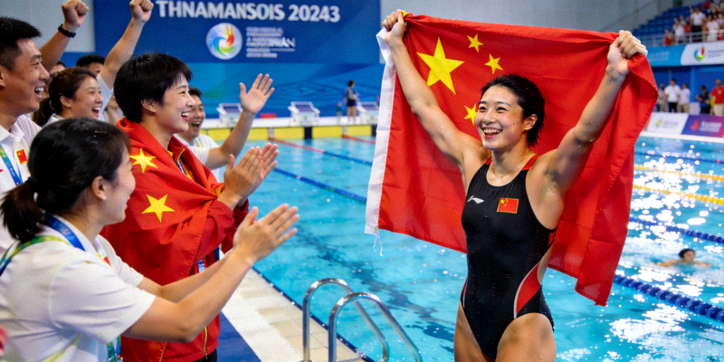 中国女子游泳运动员在亚运会夺冠后身披国旗庆祝
